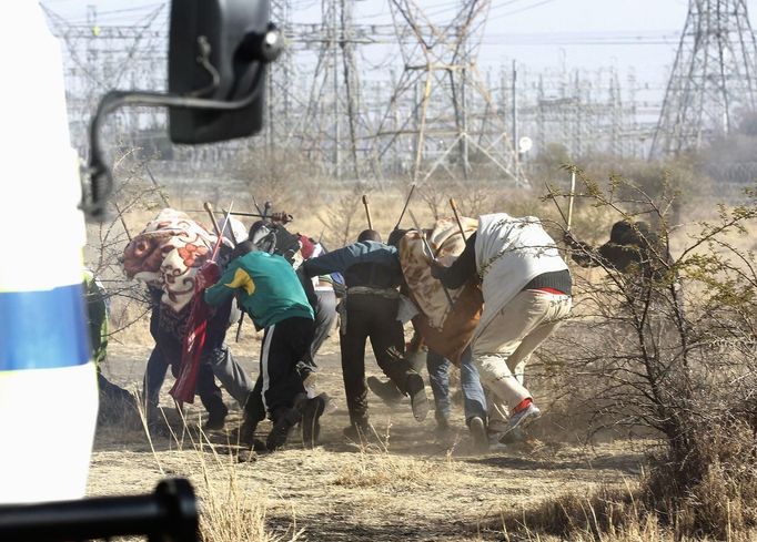 Protesting miners react as the police shot at them outside a South African mine in Rustenburg, 100 km (62 miles) northwest of Johannesburg, August 16, 2012. South African police opened fire on Thursday against thousands of striking miners armed with machetes and sticks at Lonmin's Marikana platinum mine, leaving several bloodied corpses lying on the ground. A Reuters cameraman said he saw at least seven bodies after the shooting, which occurred when police laying out barricades of barbed wire were outflanked by some of an estimated 3,000 miners massed on a rocky outcrop near the mine, 100 km (60 miles) northwest of Johannesburg. REUTERS/Siphiwe Sibeko (SOUTH AFRICA - Tags: CIVIL UNREST CRIME LAW BUSINESS EMPLOYMENT) Published: Srp. 16, 2012, 6:54 odp.