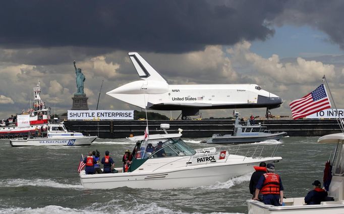 The Space Shuttle Enterprise, passes the Statue of Liberty as it rides on a barge in New York harbor, June 6, 2012. The Space Shuttle Enterprise was being moved up the Hudson River to be placed at the Intrepid Sea, Air and Space Museum. REUTERS/Mike Segar (UNITED STATES - Tags: TRANSPORT SCIENCE TECHNOLOGY) Published: Čer. 6, 2012, 5:12 odp.