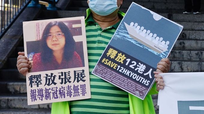 Prodemokratický aktivista drží před úřadem čínské vlády v Hongkongu transparenty s fotografií čínské občanské novinářky Čang Čan, 28. prosince 2020.
