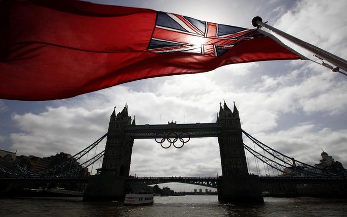 A flag on the back of a river boat flutters above Tower Bridge after the Olympic Rings were lowered into position for display from the walkways in central London, June 27, 2012. The London 2012 Olympic games will begin on July 27. REUTERS/Andrew Winning (BRITAIN - Tags: CITYSPACE SPORT OLYMPICS TPX IMAGES OF THE DAY) Published: Čer. 27, 2012, 10:50 dop.