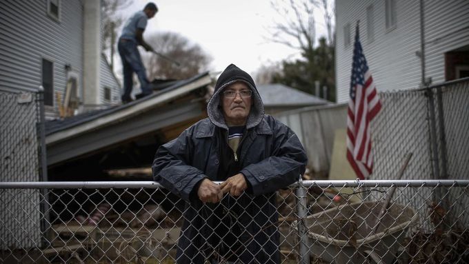 Paul Hernandez poses for a photograph in his front yard as a worker removes the collapsed remains of a portion of his home destroyed when Hurricane Sandy struck in New Dorp Beach, Staten Island November 14, 2012. Hernandez said he and other residents were angry at New York city officials for not doing more to protect their neighbourhood from the ocean and the prospect of flooding. Picture taken November 14, 2012. REUTERS/Mike Segar (UNITED STATES - Tags: DISASTER ENVIRONMENT TPX IMAGES OF THE DAY) ATTENTION EDITORS PICTURE 13 19 FOR PACKAGE 'SURVIVING SANDY' SEARCH 'SEGAR SANDY' FOR ALL PICTURES Published: Lis. 20, 2012, 3:31 odp.