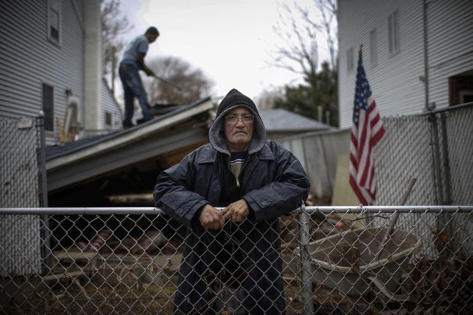 Paul Hernandez poses for a photograph in his front yard as a worker removes the collapsed remains of a portion of his home destroyed when Hurricane Sandy struck in New Dorp Beach, Staten Island November 14, 2012. Hernandez said he and other residents were angry at New York city officials for not doing more to protect their neighbourhood from the ocean and the prospect of flooding. Picture taken November 14, 2012. REUTERS/Mike Segar (UNITED STATES - Tags: DISASTER ENVIRONMENT TPX IMAGES OF THE DAY) ATTENTION EDITORS PICTURE 13 19 FOR PACKAGE 'SURVIVING SANDY' SEARCH 'SEGAR SANDY' FOR ALL PICTURES Published: Lis. 20, 2012, 3:31 odp.