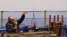 The Empire State Building is seen behind an iron worker as he stands next to protective netting on the 100th story of One World Trade Center in New York, April 30, 2012. The addition of iron columns to the 100th story pushed the height of One World Trade above that of the Empire State Building today. REUTERS/Lucas Jackson (UNITED STATES - Tags: CITYSPACE SOCIETY) Published: Dub. 30, 2012, 11:46 odp.