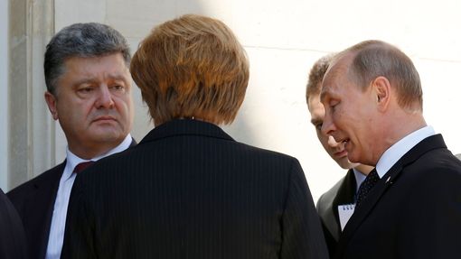 Prezidenti Petro Porošenko (vlevo) a Vladimir Putin (vpravo) se poprvé potkali, a to na oslavách výročí invaze v Normandii. Přihlížela tomu Angela Merkelová.