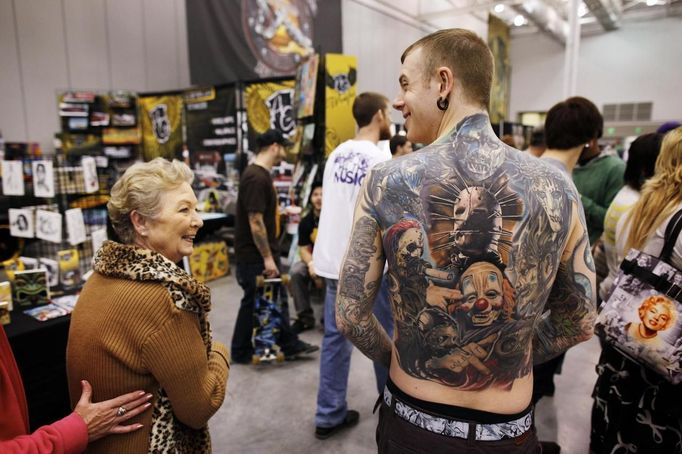 David Billings, from Abingdon, Maryland, wears a full-back tattoo featuring all nine members of his favorite band, Slipknot, as a woman admires the art at the Hampton Roads Tattoo Festival in Virginia March 2, 2012. Billings says he has had over 150 hours of tattoo work done over a 12 year period, now covering over half his body. He says tattoos are now as mainstream as Coca Cola. Picture taken March 2, 2012. REUTERS/Larry Downing (UNITED STATES - Tags: SOCIETY) ATTENTION EDITORS PICTURE 10 OF 31 FOR PACKAGE 'ADDICTED TO THE NEEDLE' TO FIND ALL PICTURES SEARCH 'ADDICTED NEEDLE' Published: Čer. 29, 2012, 12:59 odp.