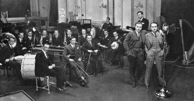 Jan Werich (vlevo) a Jiří Voskovec s Ježkovým orchestem při nahrávání gramofonové desky v roce 1932.