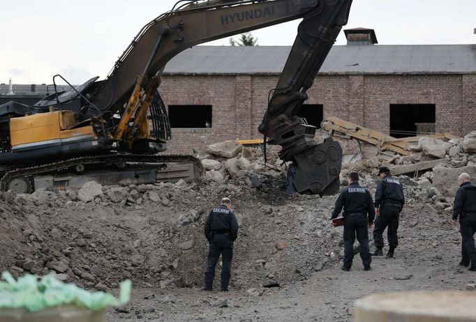 Vyšetřovatelé obhlížejí bagr po výbuchu bomby.