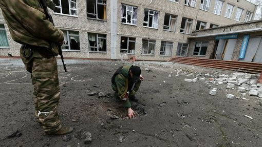 Ohledání kráteru po výbuchu střely, který poničil školu ve městě Horlivka v doněckém regionu na Ukrajině drženém proruskými separatisty. 25. února 2022.