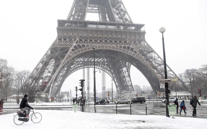 A man rides bicycle as he makes his way along a snow-covered sidewalk near the Eiffel Tower in Paris March 12, 2013 as winter weather with snow and freezing temperatures returns to northern France. REUTERS/John Schults (FRANCE - Tags: ENVIRONMENT CITYSPACE) Published: Bře. 12, 2013, 3:19 odp.