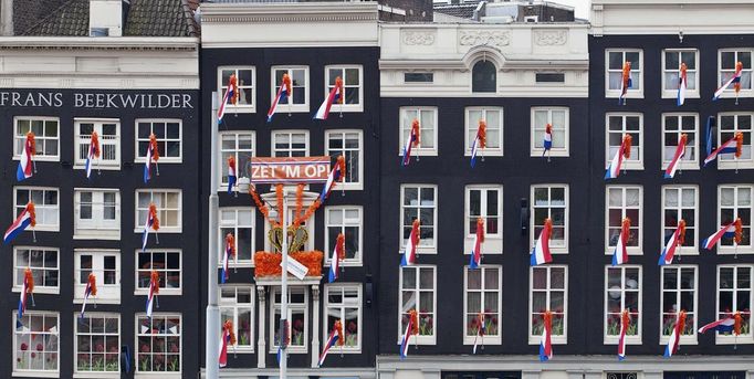 Dutch national flags hang from windows overlooking Central Station in Amsterdam April 28, 2013. The Netherlands is preparing for Queen's Day on April 30, which will also mark the abdication of Queen Beatrix and the investiture of her eldest son Willem-Alexander. REUTERS/Cris Toala Olivares(NETHERLANDS - Tags: ROYALS POLITICS TRAVEL) Published: Dub. 28, 2013, 2:58 odp.