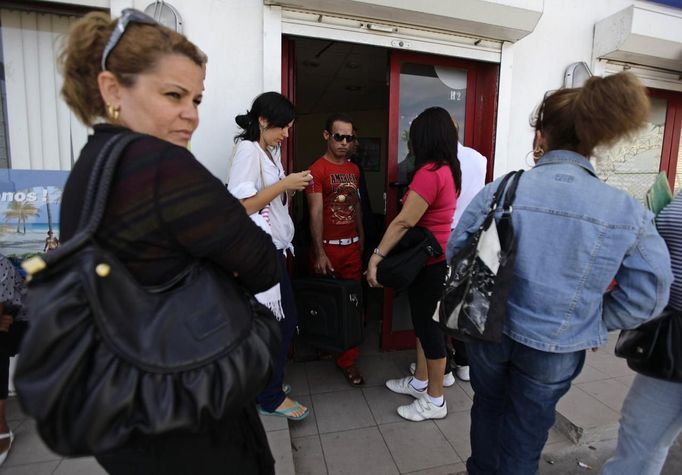 Luis Salgado (C, red shirt), nicknamed Chucho, leaves a travel agency after reconfirming his plane ticket to Miami, in Havana March 11, 2013. Chucho was granted a U.S. visa based on his father's status as legal resident in Texas, and he was reunited in Miami with his father, Jesus Salgado, who had escaped Cuba on a frail boat ten years earlier. The Salgados are among many Cubans taking advantage of Cuba's new travel policy in place since last January, which allows citizens to leave the country with just a passport and no need for much-hated exit visas required since 1961. Picture taken March 11, 2013. REUTERS/Desmond Boylan (CUBA - Tags: POLITICS SOCIETY) Published: Dub. 11, 2013, 1:56 odp.