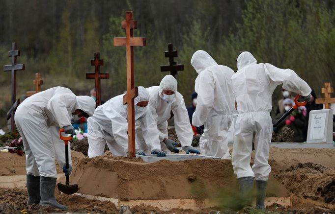 Hrobníci ukládají do země rakev s ostatky jedné z oběti nemoci covid-19 v Petrohradu.