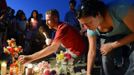 Justin Konye (C) places candles with other mourners during a vigil for victims behind a theater where a gunman open fire at moviegoers in Aurora, Colorado July 20, 2012. A total of 71 people were shot in Friday's rampage at the Denver-area movie theater that has left 12 people dead, the local police chief said. The suspect, identified by police as James Eagan Holmes, 24, also booby-trapped his Aurora apartment with sophisticated explosives, creating a hazard for law-enforcement and bomb squad officers who swarmed to the scene. REUTERS/ Jeremy Papasso (UNITED STATES - Tags: CRIME LAW) Published: Čec. 21, 2012, 3:55 dop.