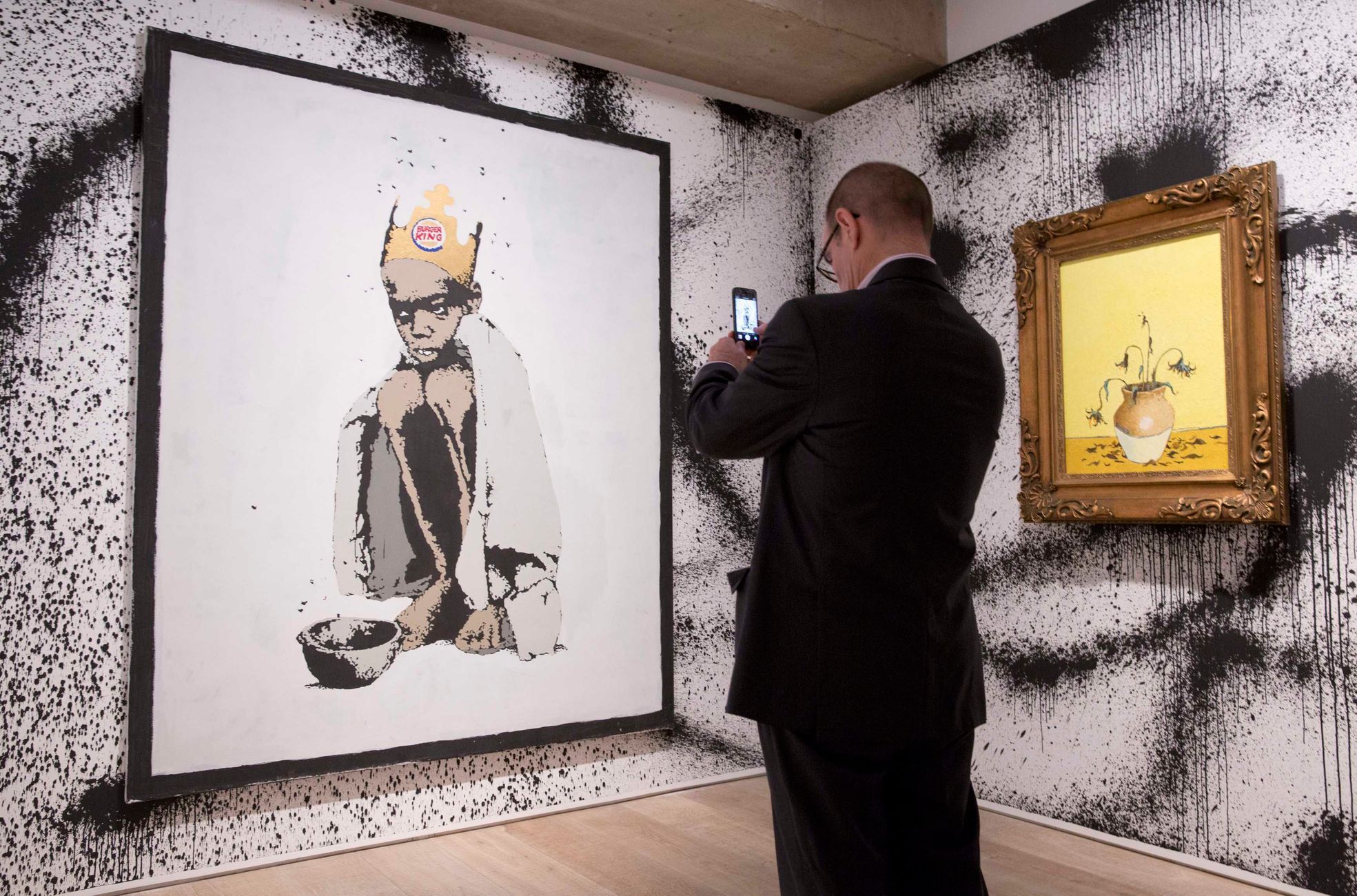 A man photographs &quot;Burger King&quot; at the Banksy: The Unauthorised Retrospective exhibition at Sotheby's S2 Gallery in London