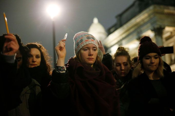 K uctění památky obětem zvedají lidé do výšky ruku s pery a tužkami na Trafalgar Square v Londýně.