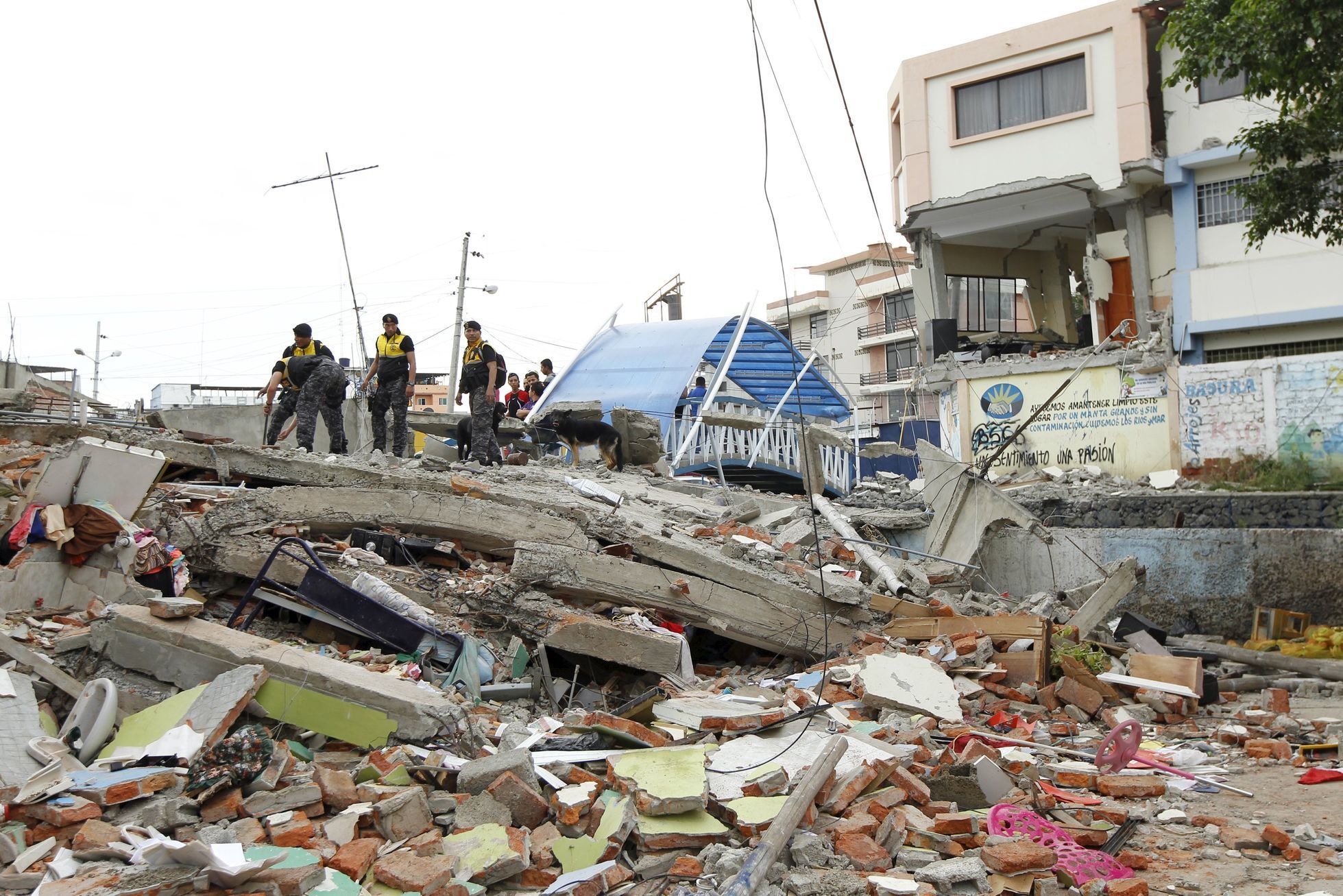 Police officers stand on debris after an earthquake struck off Ecuador's Pacific coast, at Tarqui neighborhood in Manta