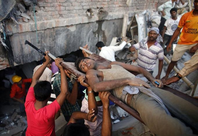 Rescue workers carry a garment worker who was trapped in the Rana Plaza building which collapsed, in Savar, 30 km (19 miles) outside Dhaka April 24, 2013. A block housing garment factories and shops collapsed in Bangladesh on Wednesday, killing nearly 100 people and injuring more than a thousand, officials said.REUTERS/Andrew Biraj (BANGLADESH - Tags: DISASTER BUSINESS) Published: Dub. 24, 2013, 3:42 odp.