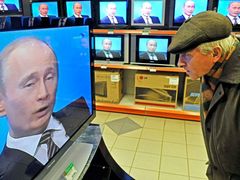 Ruský stařík poslouchá projev premiéra Putina v jedné z moskevských prodejen s elektronikou