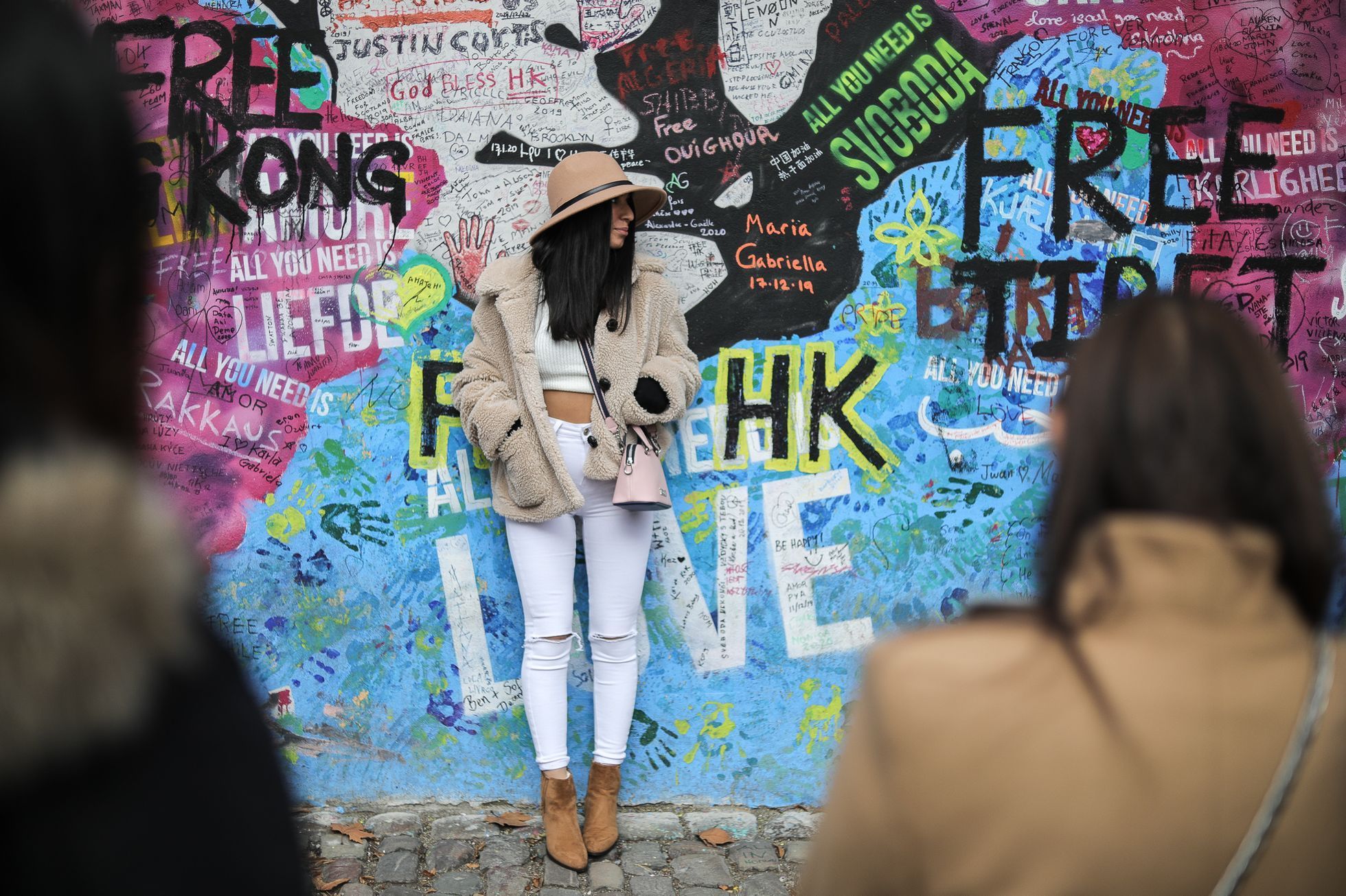 Lennonova zeď po třech měsících od malování - turisté, graffiti