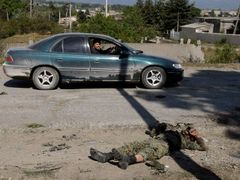 Auto projíždí kolem těla mrtvého gruzínského vojáka na okraji Cchinavali.