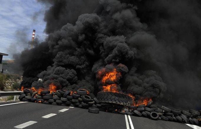 Burning tires are seen in the N0-630 road during a miner demonstration in La Robla, near Leon, northern Spain June 20, 2012. The miners were protesting against the government's proposal to decrease funding for coal production. REUTERS/Eloy Alonso (SPAIN - Tags: CIVIL UNREST POLITICS BUSINESS EMPLOYMENT) Published: Čer. 20, 2012, 1:28 odp.