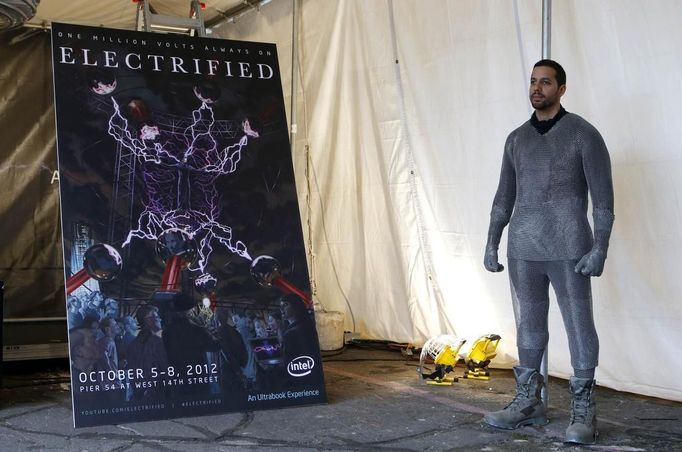 Magician David Blaine stands near a poster promoting his upcoming performance "Electrified" during a press briefing in New York, October 2, 2012. During the performance Blaine will wear a custom made metal suit and will stand on a 20-foot-high (6 meter) platform on New York City's Pier 54 on the edge of the Hudson River while surrounded by seven metallic orbs, or tesla coils, that will stream 1 million volts of electricity around him for 3 days and nights. REUTERS/Mike Segar (UNITED STATES - Tags: ENTERTAINMENT SOCIETY) Published: Říj. 2, 2012, 7:06 odp.