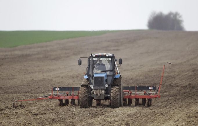 A villager operating a tractor sows barley at the village of Novosyolki