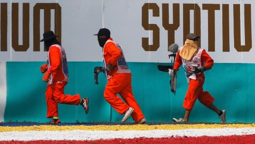 Track officials rush to remove debris from the track during the Malaysian F1 Grand Prix at Sepang International Circuit outside Kuala Lumpur, March 30, 2014. REUTERS/Edga
