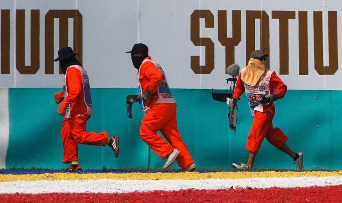 Track officials rush to remove debris from the track during the Malaysian F1 Grand Prix at Sepang International Circuit outside Kuala Lumpur, March 30, 2014. REUTERS/Edga