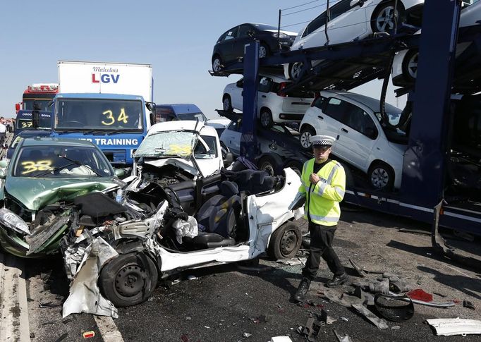 A police officer reacts as he stands amongst the wreckage of some of the 100 vehicles involved in multiple collisions, which took place in dense fog during the morning rush hour, on the Sheppey Bridge in Kent, east of London, September 5, 2013. Eight people were seriously injured and dozens hurt in the multiple crashes.