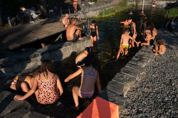 Děti skáčou z mola a hrají si na kamenité kaskádě, kterou stéká pramen do nádrže.