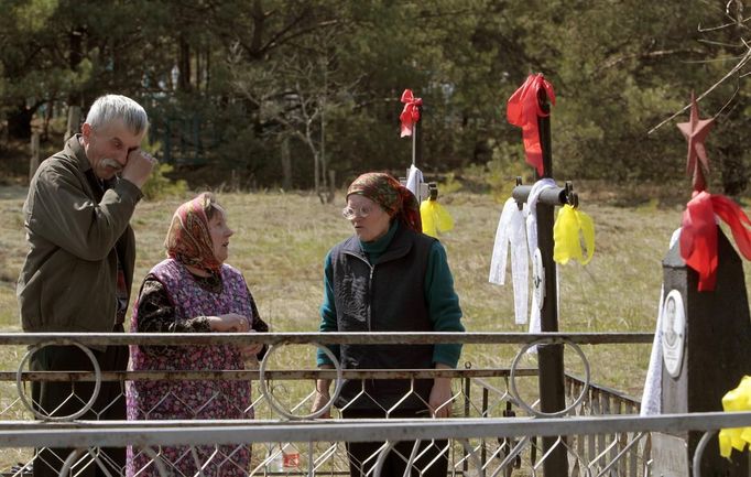 People stand at the grave of a relative on the eve of Radunitsa in the abandoned village of Tulgovichi