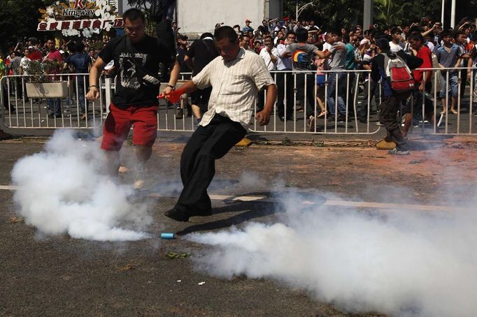 A demonstrator tries to kick a tear gas canister away during a protest against Japan's decision to purchase disputed islands, which Japan calls the Senkaku and China calls the Diaoyu, in Shenzhen, south China's Guangdong province September 16, 2012. Torrid protests against Japan flared in Chinese cities for a second day on Sunday, with the government struggling to find a balance between venting public anger and containing violence that could backfire ahead of a delicate leadership succession. REUTERS/Tyrone Siu (CHINA - Tags: POLITICS CIVIL UNREST)