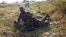 A SPLA soldier looks at warplanes as he lies on the ground to take cover beside a road during an air strike in Rubkona