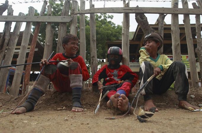 Endiansyah Mohammad (L) chats with friends before a race at Panda racetrack outside Bima, November 18, 2012. Dozens of child jockeys, some as young as eight-years-old take part in the races. Involving nearly 600 horses they take place around a dusty, oval track of 1,400 meters (nearly one mile). The reward, for the winner is a handful of cash for his family, and glory for the jockey. The grand prize is one million rupiah ($100). Those who win their groups get two cows. The chairman of the races' organising team, Hajji Sukri, denies that there is any danger to the children saying they are all skilful riders and none has been killed or seriously hurt. Picture taken November 18, 2012. REUTERS/Beawiharta (INDONESIA - Tags: SPORT SOCIETY) ATTENTION EDITORS: PICTURE 21 of 25 FOR PACKAGE 'BETTING ON CHILD JOCKEYS' Published: Lis. 24, 2012, 9:17 dop.