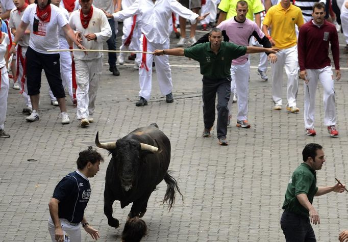 A shepherd prevents fighting bull Fugado (Runaway) from turning back at the Telefonica corner, during the third Encierro (Running Of The Bulls) at the San Fermin festival in Pamplona July 9, 2012. Three people were gored by Fugado, a 545 kg (1200 lb) bull from the Cebada Gago ranch, in a run that lasted three minutes and thirty-eight seconds. REUTERS/Vincent West (SPAIN - Tags: ANIMALS SOCIETY) Published: Čec. 9, 2012, 7:41 dop.