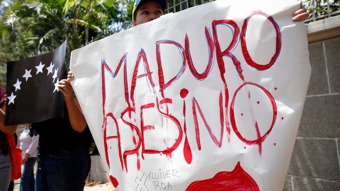 Demonstrant v Caracasu drží transparent kritizující prezidenta Madura.
