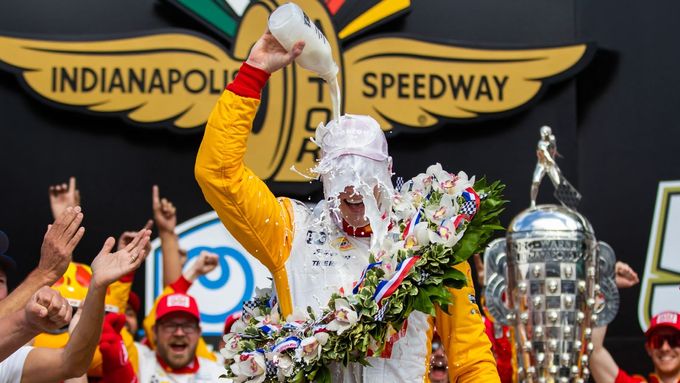 Josef Newgarden slaví vítězství v závodě na 500 mil v Indianapolisu tradičně s lahví mléka místo šampaňského.