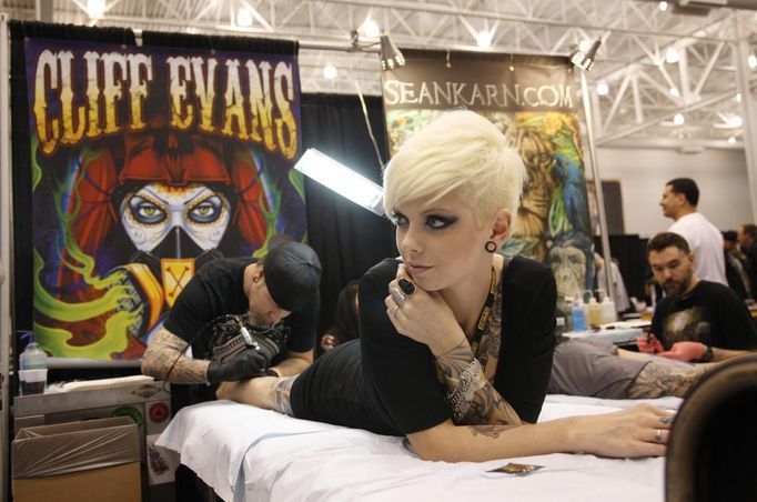 A woman lies on a table as he has a tattoo work applied to her leg by artist Cliff Evans at the Hampton Roads Tattoo Festival in Virginia March 2, 2012. The hobby of collecting tattoos has exploded into the mainstream of society with tattoo conventions and festivals held year-round across the United States. Picture taken March 2, 2012. REUTERS/Jason Reed (UNITED STATES - Tags: SOCIETY) ATTENTION EDITORS PICTURE 14 OF 31 FOR PACKAGE 'ADDICTED TO THE NEEDLE' TO FIND ALL PICTURES SEARCH 'ADDICTED NEEDLE' Published: Čer. 29, 2012, 12:59 odp.