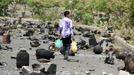 A boy walks on a street littered with cooking gas cylinders after a fire and explosions destroyed a nearby gas storage during clashes between fighters of the Popular Resi