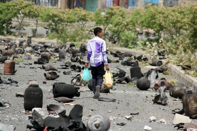 A boy walks on a street littered with cooking gas cylinders after a fire and explosions destroyed a nearby gas storage during clashes between fighters of the Popular Resi