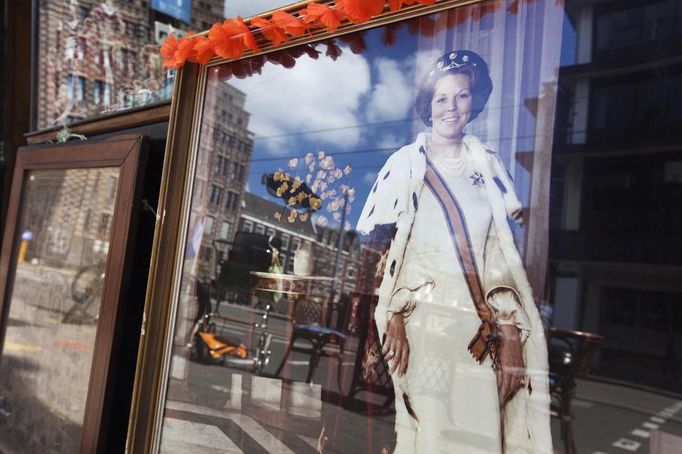 A portrait of Dutch Queen Beatrix is seen at the window of a shop, opposite the royal palace in Amsterdam April 28, 2013. The Netherlands is preparing for Queen's Day on April 30, which will also mark the abdication of Queen Beatrix and the investiture of her eldest son Willem-Alexander. REUTERS/Cris Toala Olivares(NETHERLANDS - Tags: ROYALS POLITICS TRAVEL) Published: Dub. 28, 2013, 3:07 odp.