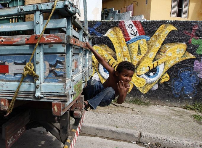 Šestiletý Ryan leze na nákladní vůz převážející pomeranče. V pozadí za ním je graffiti, které má na svědomí někdo ze skupiny mladých umělců, kteří jsou známí pod zkratkou OPNI, a kteří se snaží od roku 1997 vytvořit z brazilských ulic jednu velkou galerii a zpříjemňovat tím život ve slumech.