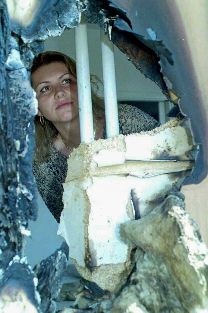 Obyvatelka českobudějovického sídliště Vltava si prohlíží otvor ve zdi, kudy vlétl do její ložnice kus ze stíhačky MiG-21 po její pondělní srážce s dalším letounem.