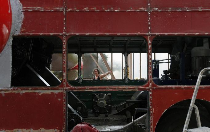 Artist David Cerny gestures at a factory hall in Prague as he works on his project to transform a London bus into a robotic sculpture May 22, 2012. The bus, which Cerny hopes could become an unofficial mascot of the London 2012 Olympic Games, does push-ups with the help of an engine powering a pair of robotic arms and the motion is accompanied by a recording of sounds evoking tough physical effort. It will be parked outside the Czech Olympic headquarters in London for the duration of the Games. Picture taken May 22, 2012. REUTERS/Petr Josek (CZECH REPUBLIC - Tags: SOCIETY SPORT OLYMPICS TRANSPORT) Published: Čec. 22, 2012, 5:47 odp.