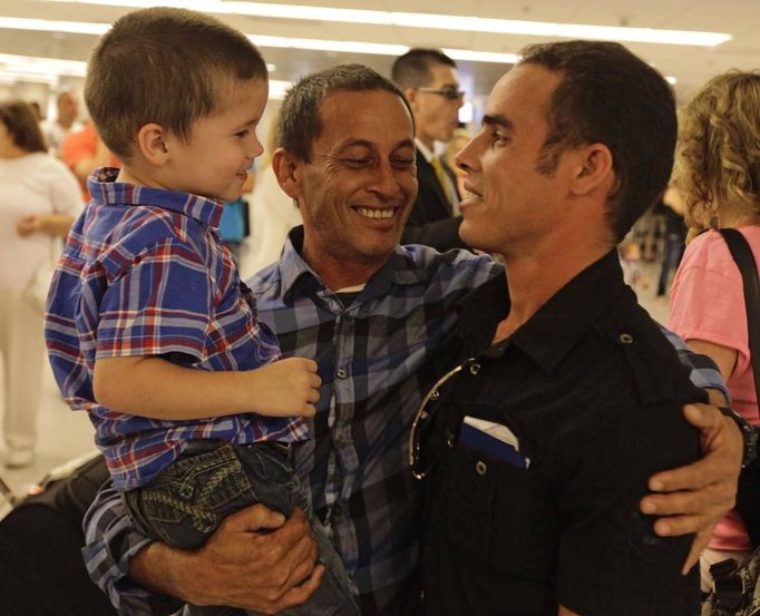 Luis Salgado (R), nicknamed Chucho, is reunited after ten years with his father, Jesus Salgado (C), and his half brother Kevin, after Luis arrived from Havana at Miami airport, March 13, 2013. Chucho was granted a U.S. visa based on his father's status as legal resident in Texas, and he was reunited in Miami with his father, who had escaped Cuba on a frail boat ten years earlier. The Salgados are among many Cubans taking advantage of Cuba's new travel policy in place since last January, which allows citizens to leave the country with just a passport and no need for much-hated exit visas required since 1961. Picture taken March 13, 2013. REUTERS/Desmond Boylan (UNITED STATES - Tags: POLITICS SOCIETY) Published: Dub. 11, 2013, 1:28 odp.