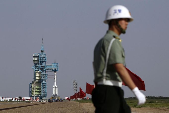 A soldier patrols in front of the launch pad holding a Long March II-F rocket loaded with a Shenzhou-9 manned spacecraft carrying Chinese astronauts Jing Haipeng, Liu Wang and Liu Yang before its launch at the Jiuquan Satellite Launch Center, Gansu province June 16, 2012. China launched the spacecraft putting its first woman, 33-year-old female fighter pilot Liu Yang, in orbit on Saturday as the country takes its latest step towards building a space station within the decade. REUTERS/Jason Lee (CHINA - Tags: MILITARY SCIENCE TECHNOLOGY) Published: Čer. 16, 2012, poledne