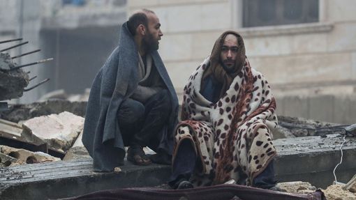 Muži odpočívají na troskách po zemětřesení v povstalci ovládaném městě Jandairis v Sýrii.