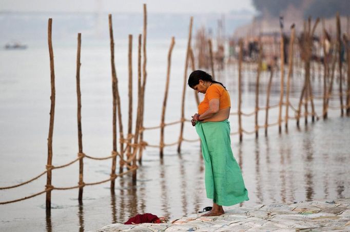 A Hindu woman gets dressed after taking a holy dip in the waters of the Ganges river ahead of the "Kumbh Mela", or Pitcher Festival, in the northern Indian city of Allahabad January 10, 2013. During the festival, hundreds of thousands of Hindus take part in a religious gathering at the banks of the river Ganges. The festival is held every 12 years in different Indian cities. REUTERS/Ahmad Masood (INDIA - Tags: RELIGION SOCIETY) Published: Led. 10, 2013, 8:33 dop.