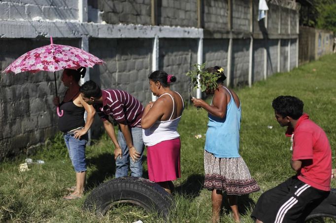 People stand near a crime scene where the dead body of a man was found after he was shot by gang members in San Pedro Sula March 28, 2013. San Pedro Sula, the country's second largest city after Tegucigalpa, has a homicide rate of 169 per 100,000 people and was named the world's most violent city for a second year in a row. Lax laws allow civilians to own up to five personal guns. Arms trafficking has flooded the country with nearly 70% illegal firearms. 83.4% of homicides are by firearms, compared to 60% in the United States. Picture taken March 28, 2013. REUTERS/Jorge Cabrera (HONDURAS - Tags: CRIME LAW CIVIL UNREST HEALTH) ATTENTION EDITORS: PICTURE 32 OF 39 FOR PACKAGE 'GUN CULTURE - HONDURAS' SEARCH 'HONDURAS GUN' FOR ALL IMAGES Published: Dub. 5, 2013, 11:15 dop.